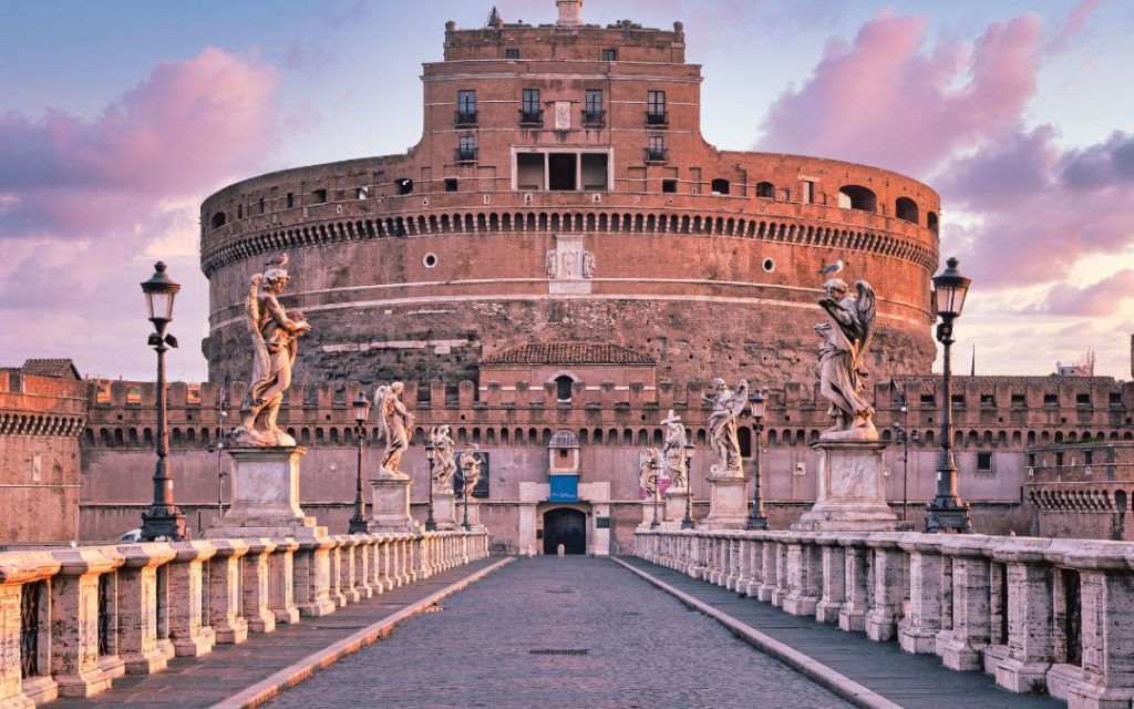 Zamek św. Anioła w Rzymie widziany z mostu Ponte Sant'Angelo z rzeźbami aniołów na tle wieczornego nieba