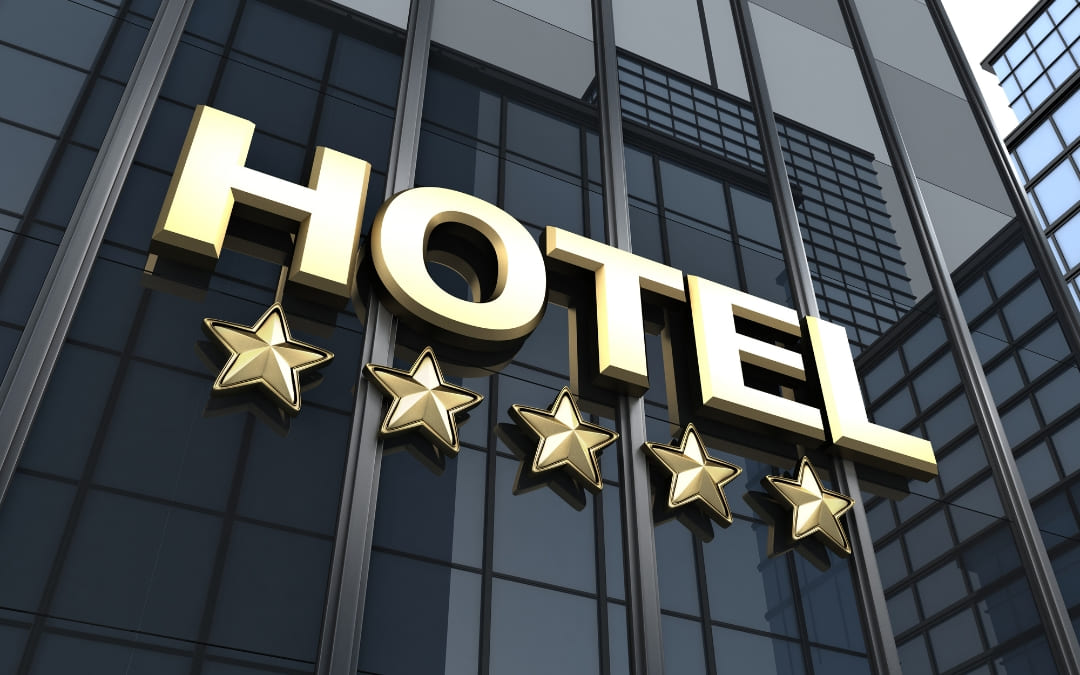 Złoty napis HOTEL i pięć gwiazdek na nowoczesnej szklanej elewacji budynku