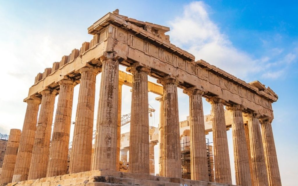 Antyczne kolumny greckiej świątyni Partenon na Akropolu pod jasnym, błękitnym niebem.