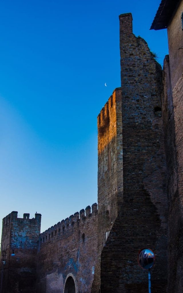 Ceglane mury i wieża dzielnicy San Lorenzo w Rzymie oświetlone o zmierzchu z księżycem w tle
