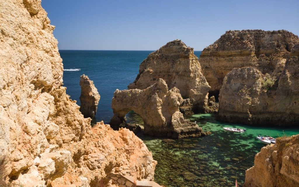 Charakterystyczne skalne klify i formacje wyłaniające się z błękitnego oceanu na wybrzeżu Algarve w Portugalii.