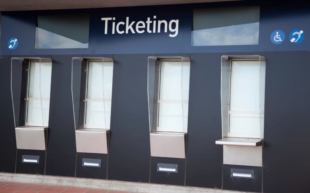 Cztery nowoczesne okienka kasowe z napisem Ticketing i osłonami z pleksi