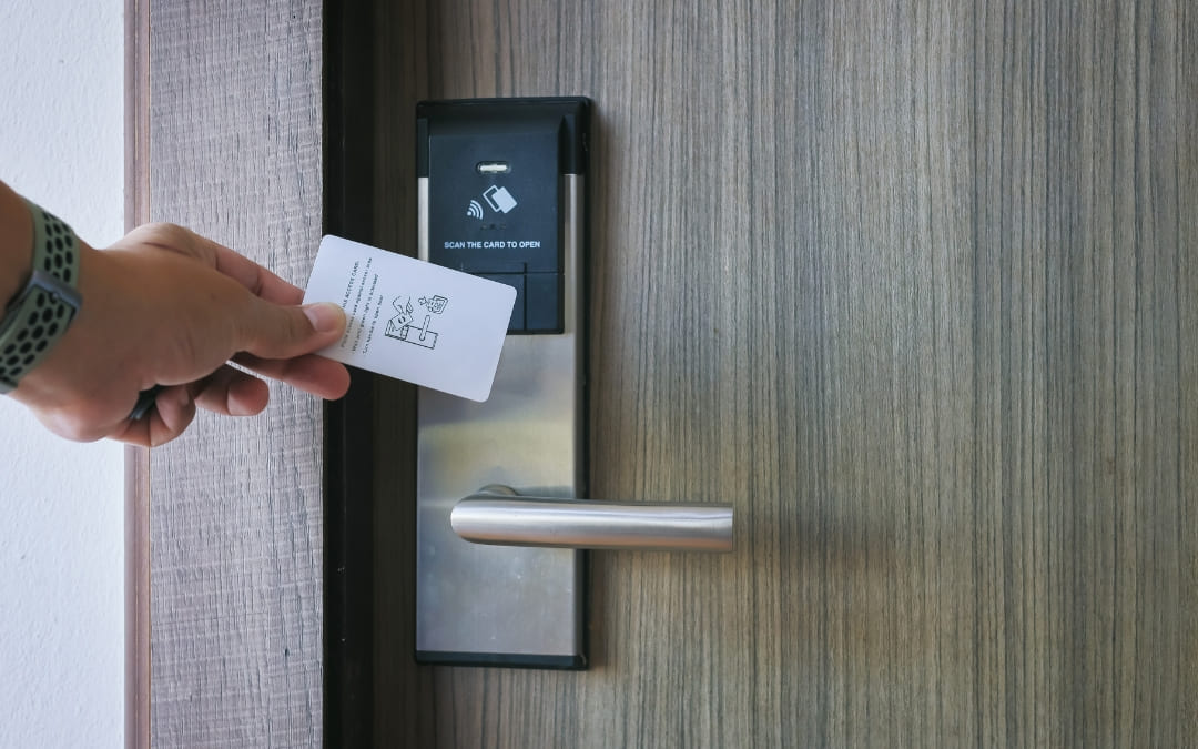 Dłoń przykładająca kartę magnetyczną do elektronicznego zamka w drzwiach pokoju hotelowego