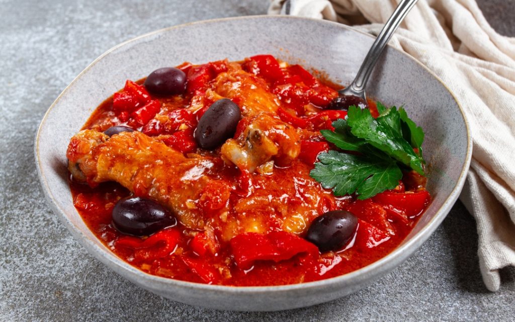 Duszona ryba w sosie pomidorowym z oliwkami i pietruszką w szarej misce