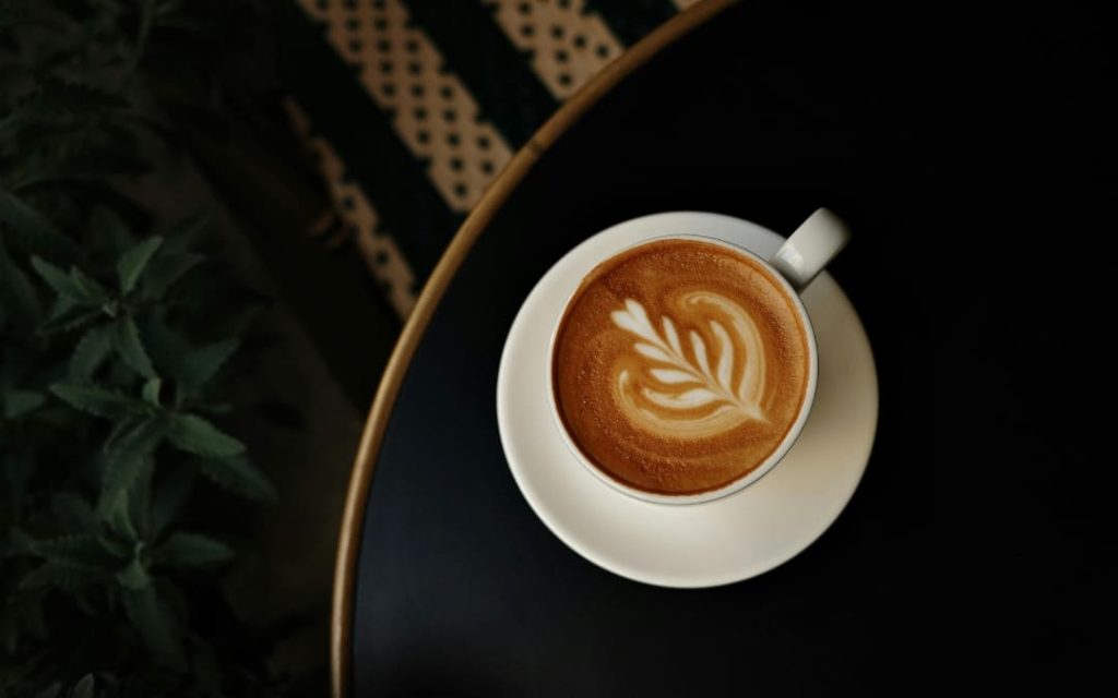 Filiżanka cappuccino z latte art widoczna z góry na ciemnym tle