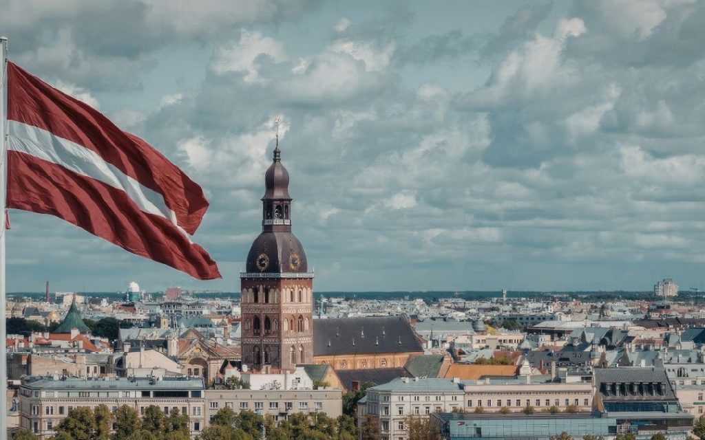 Flaga Łotwy na wietrze z panoramą rygi
