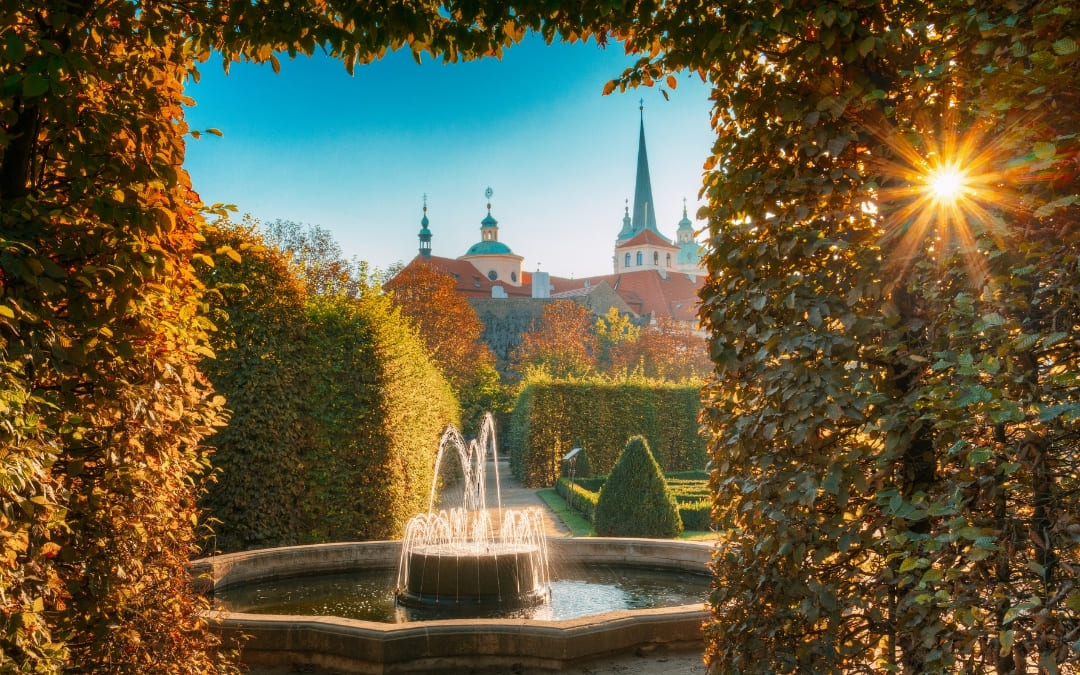 Fontanna w Ogrodzie Waldsteńskim w Pradze otoczona jesienną roślinnością z promieniami słońca