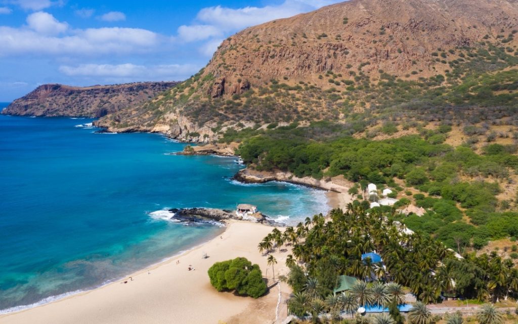 Górzyste wybrzeże wyspy z piaszczystą zatoką i turkusową wodą oceanu.