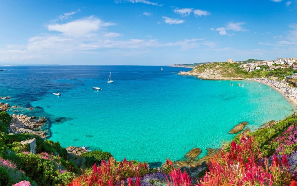 Krystalicznie czysta, szmaragdowa woda w zatoce w Sardynii z widokiem na wybrzeże.