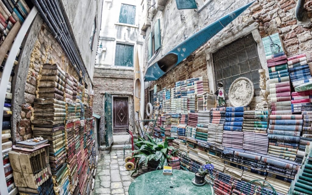 Libreria Acqua Alta - ksiązki ułożone wzdłuż kamienic przy wejściu do księgarni