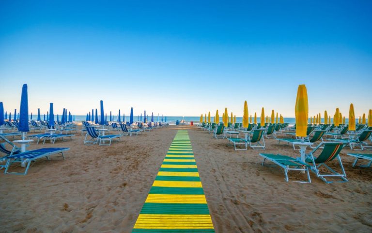Lido di Jesolo w słoneczny dzień z złożonymi parasolami i leżakami