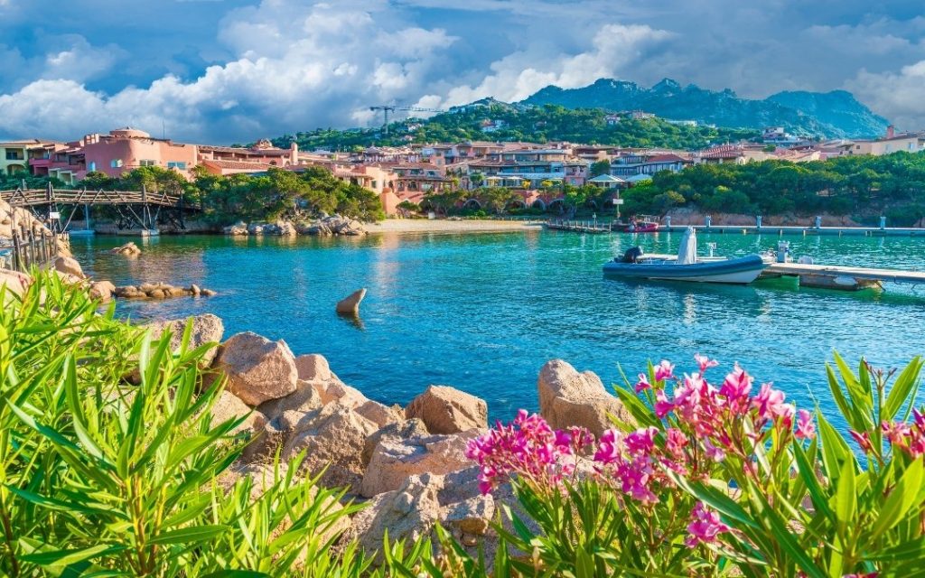 Panorama malowniczej zatoki na Sardynii z łodzią w turkusowej wodzie.