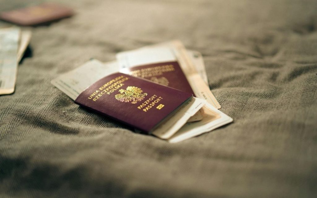 Paszporty i bilety lotnicze leżące na łóżku, przygotowane do spakowania na nadchodzący wyjazd.