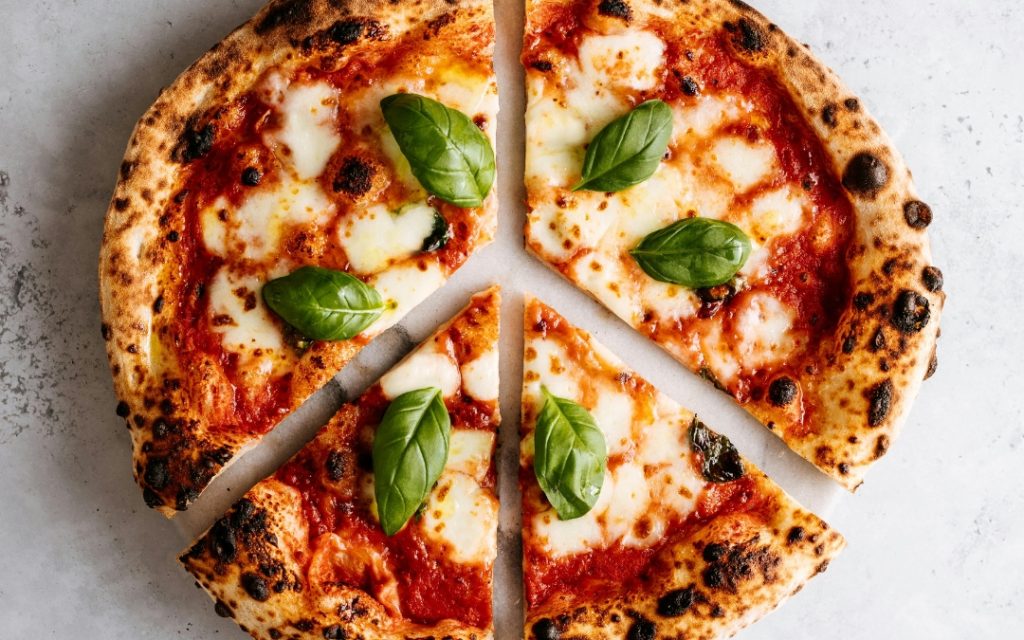 Pizza margherita z mozzarellą i świeżą bazylią na chrupiącym cieście z pieca opalanego drewnem