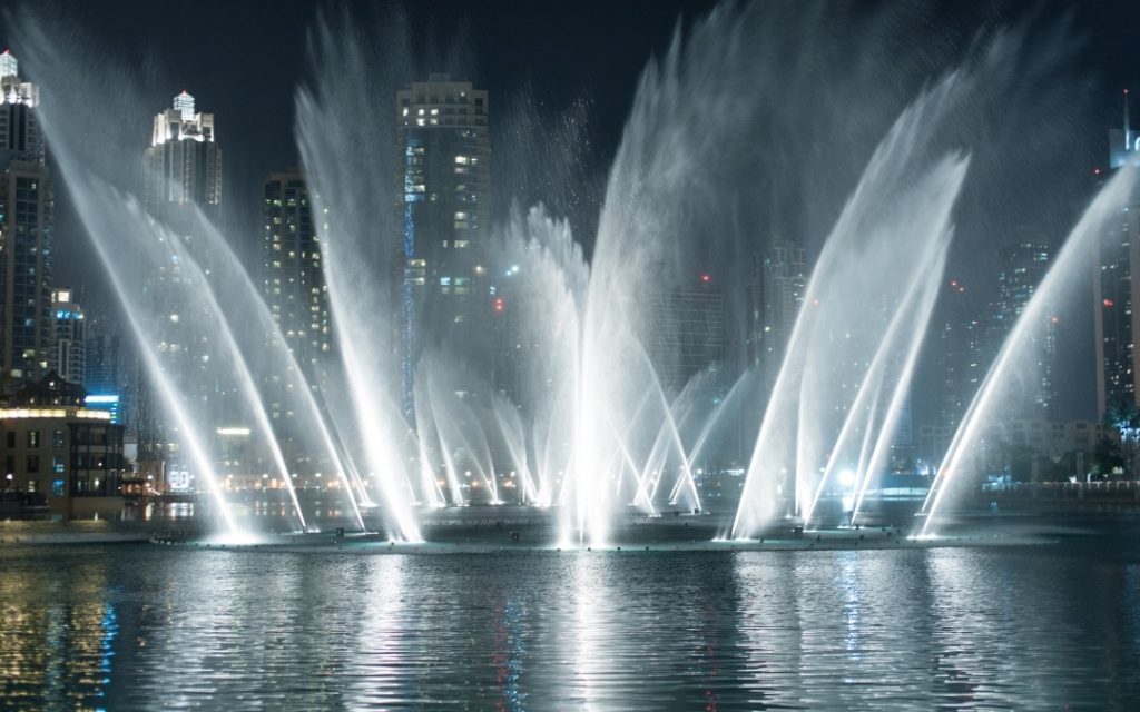 Podświetlone fontanny w Dubaju, pokaz wodny na tle nowoczesnych wieżowców nocą.
