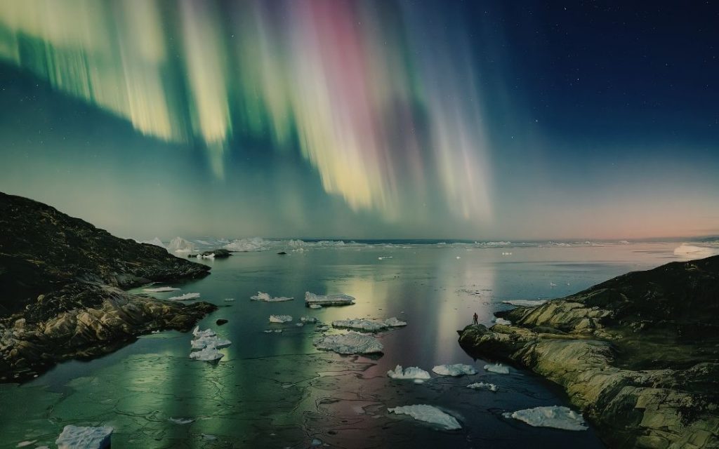 Spektakularna zorza polarna nad lodowcowym krajobrazem Islandii w mroźną noc.