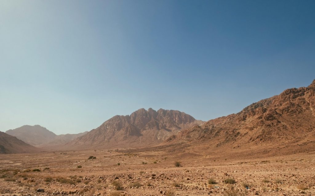 Surowy, pustynny krajobraz z monumentalnymi, piaszczystymi wzgórzami pod bezchmurnym niebem w Jordanii.