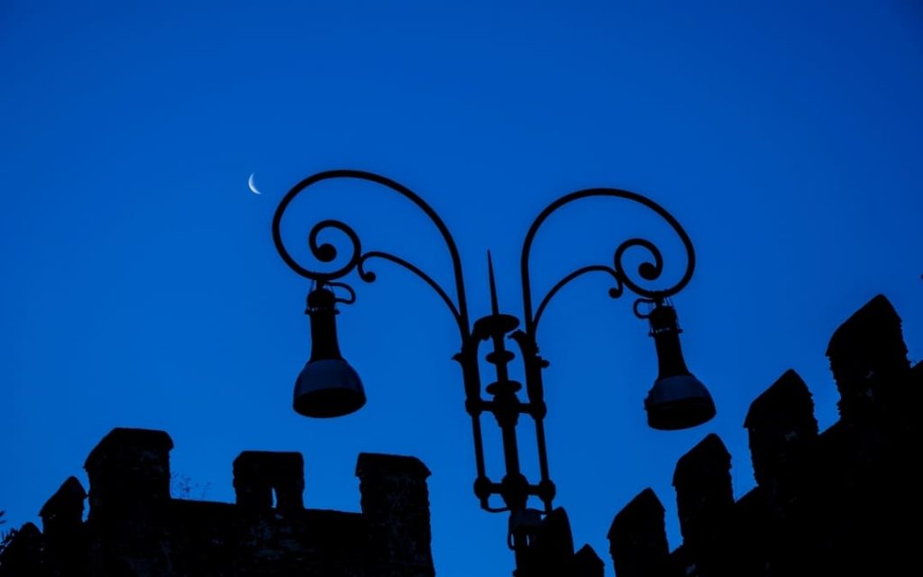 Sylwetka ozdobnej latarni ulicznej na tle granatowego nieba przy murach San Lorenzo w Rzymie