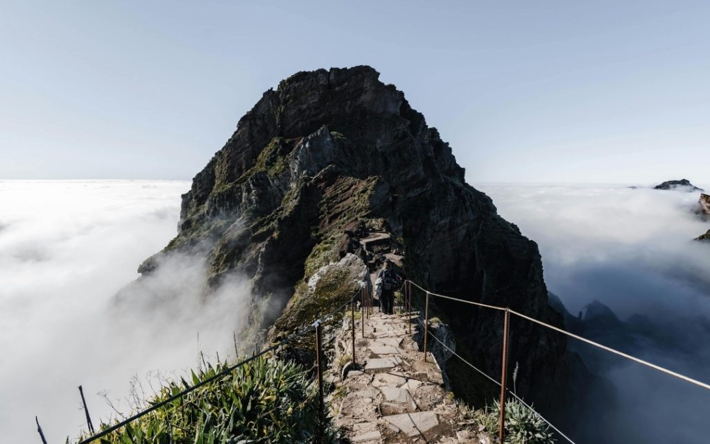 Szlak trekkingowy na Maderze prowadzący przez strome zbocza gór ponad poziomem chmur.