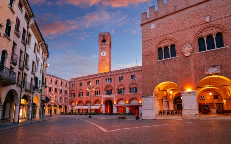 Treviso tuż po zachodzie słońca z rozświetlonymi budynkami i nastrojową atmosferą miasta