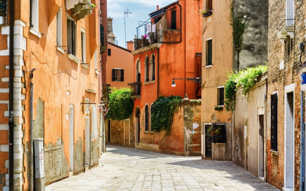 Wąska uliczka Wenecji z bujną roślinnością na budynkach 