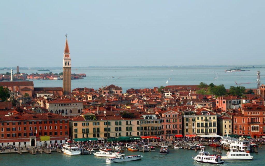 Widok na Riva degli Schiavoni w Wenecji z kolorowymi kamienicami, turystami i łodziami przy brzegu