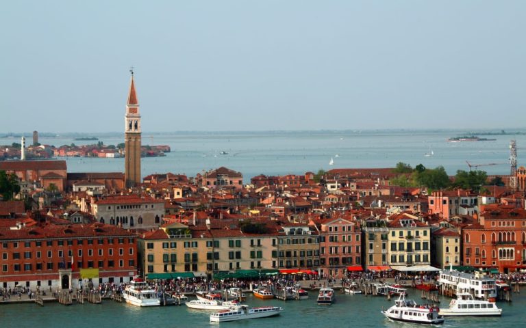 Widok na Riva degli Schiavoni w Wenecji z kolorowymi kamienicami, turystami i łodziami przy brzegu