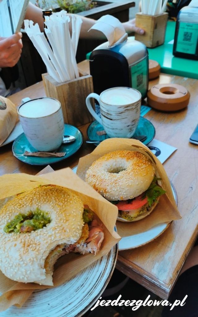 Widok z góry na stół z kawą, sokiem i dwoma bajglami z łososiem w kawiarni