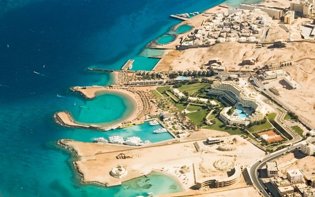 Widok z lotu ptaka na luksusowy resort nad Morzem Czerwonym z turkusowymi lagunami i basenami.