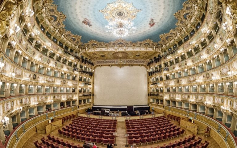 Wnętrze Teatro La Fenice w Wenecji z bogato zdobionymi balkonami i czerwonymi fotelami