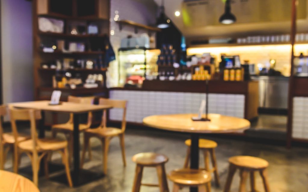 Wnętrze kawiarni z wysokimi stołkami, barem i ciepłym oświetleniem
