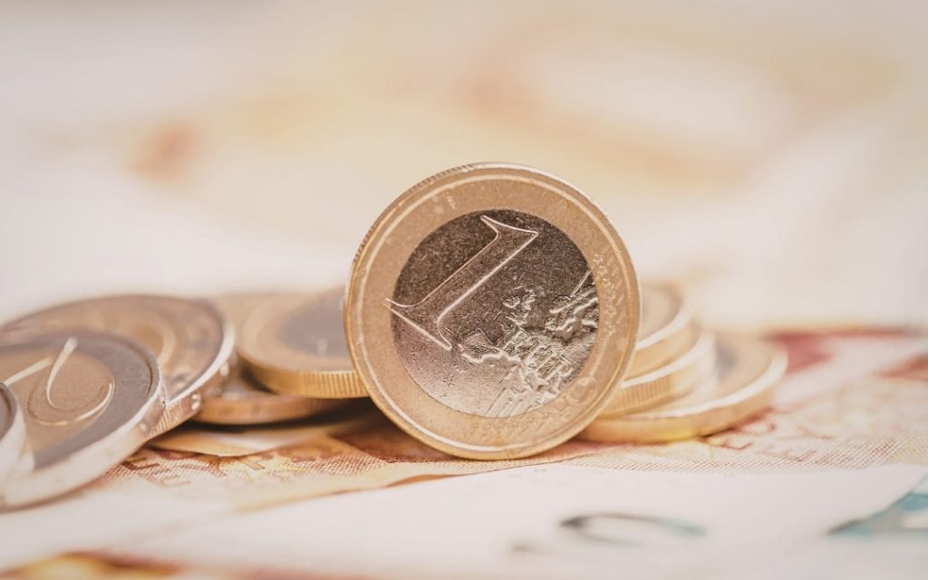 Zbliżenie na monetę o nominale 1 euro stojącą pionowo na stole
