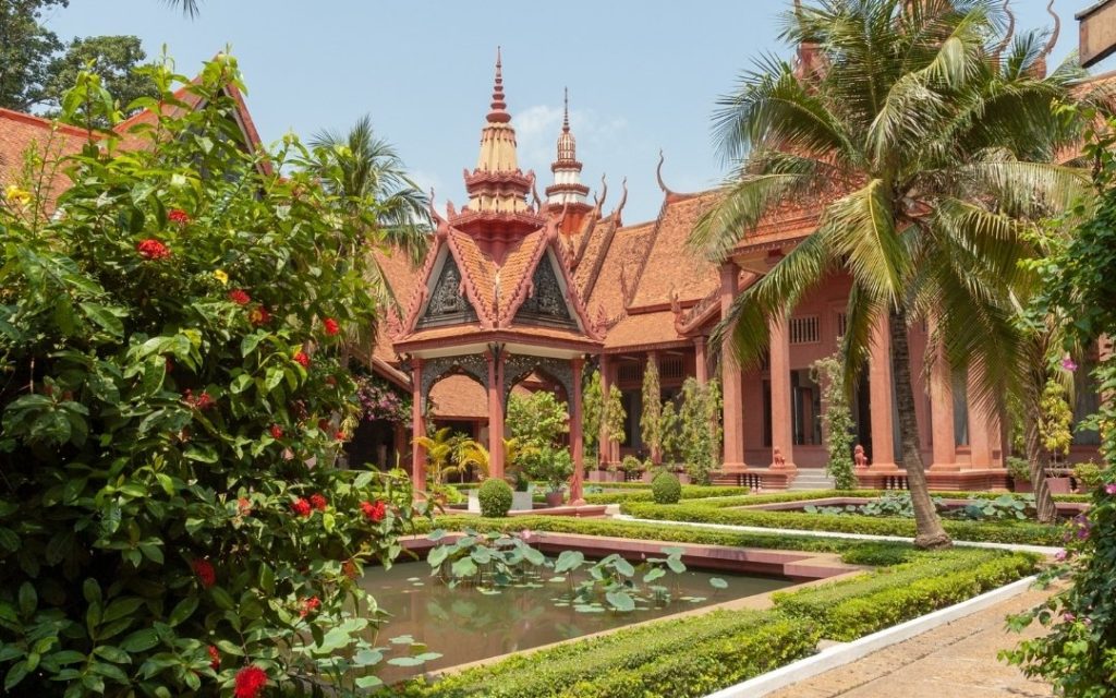 Zdobiona architektura buddyjskiej świątyni w Kambodży otoczona egzotycznym ogrodem i palmami.