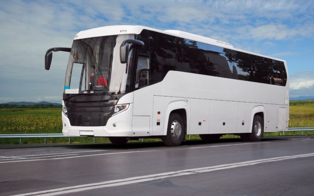 Biały autokar na tle zielonych pól