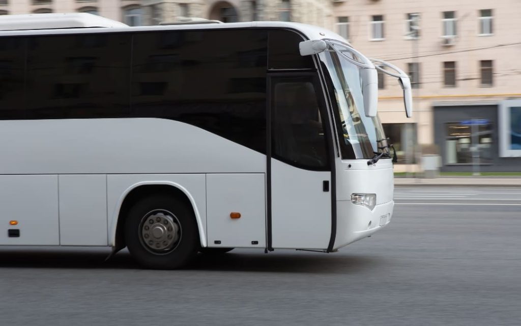 Biały autokar turystyczny jadący przez miasto