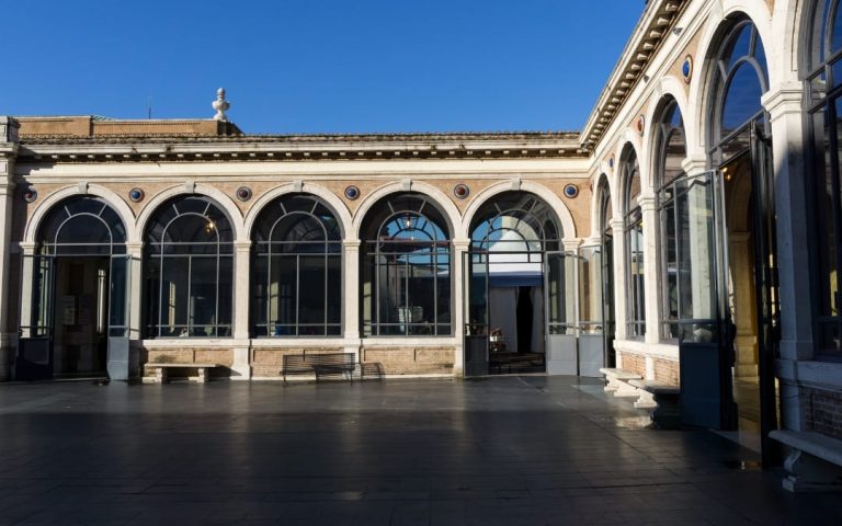 Dziedziniec Muzeum Watykańskiego z arkadami i wielkimi przeszklonymi oknami pod błękitnym niebem