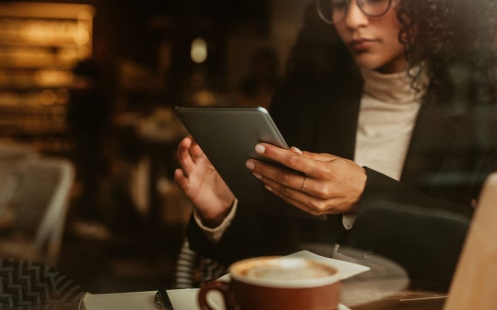 Osoba trzymająca telefon i paszport przy walizce podczas podróży
