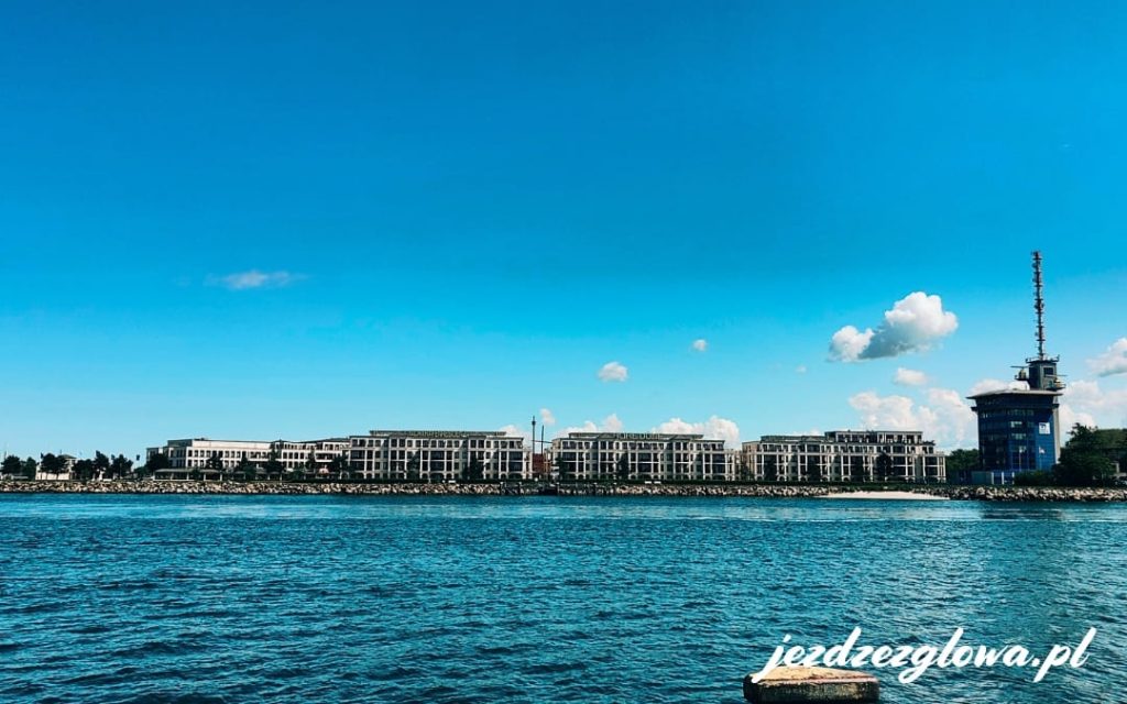 Panorama nabrzeża w Warnemunde z luksusowym hotelem i wieżą kontroli portu nad wodą