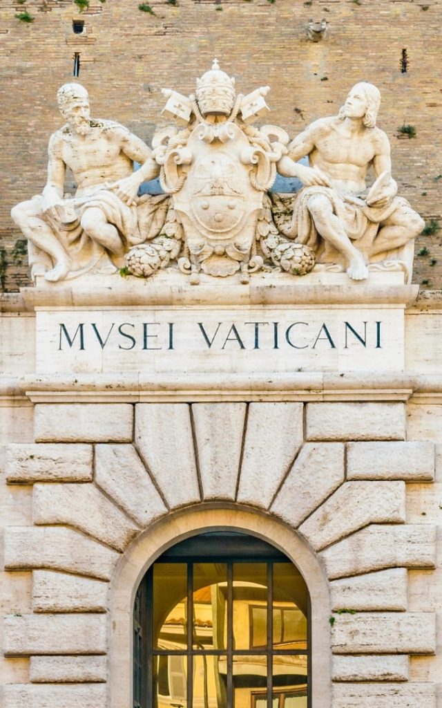 Wejście główne do Muzeów Watykańskich z napisem „Musei Vaticani" i rzeźbami nad bramą