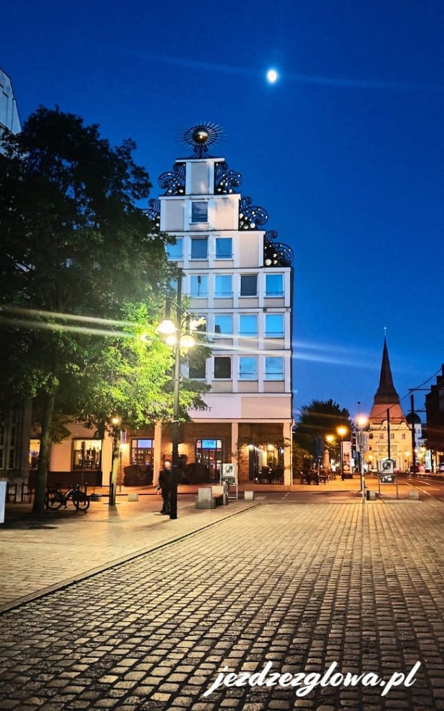 Wieczorny widok na hotel Vienna House Sonne przy Neuer Markt w Rostocku, w świetle ulicznych latarni