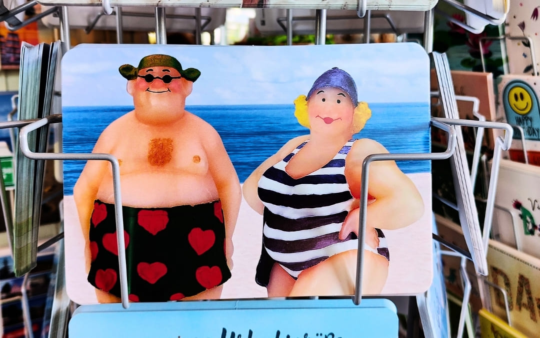 Zabawna pocztówka przedstawiająca pulchnych wczasowiczów relaksujących się na plaży