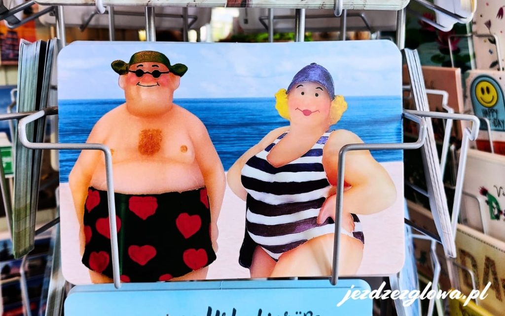Zabawna pocztówka przedstawiająca pulchnych wczasowiczów relaksujących się na plaży