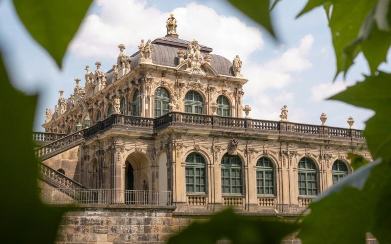 Barokowy pawilon Zwingeru w Dreźnie widziany zza zielonych liści