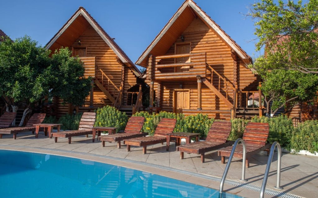 Drewniane domki bungalow z basenem i leżakami w ośrodku wakacyjnym