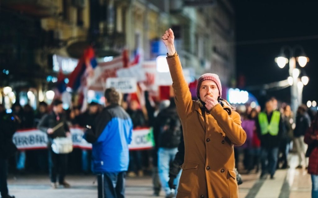 Nocna demonstracja z uczestnikiem trzymającym pięść w górze