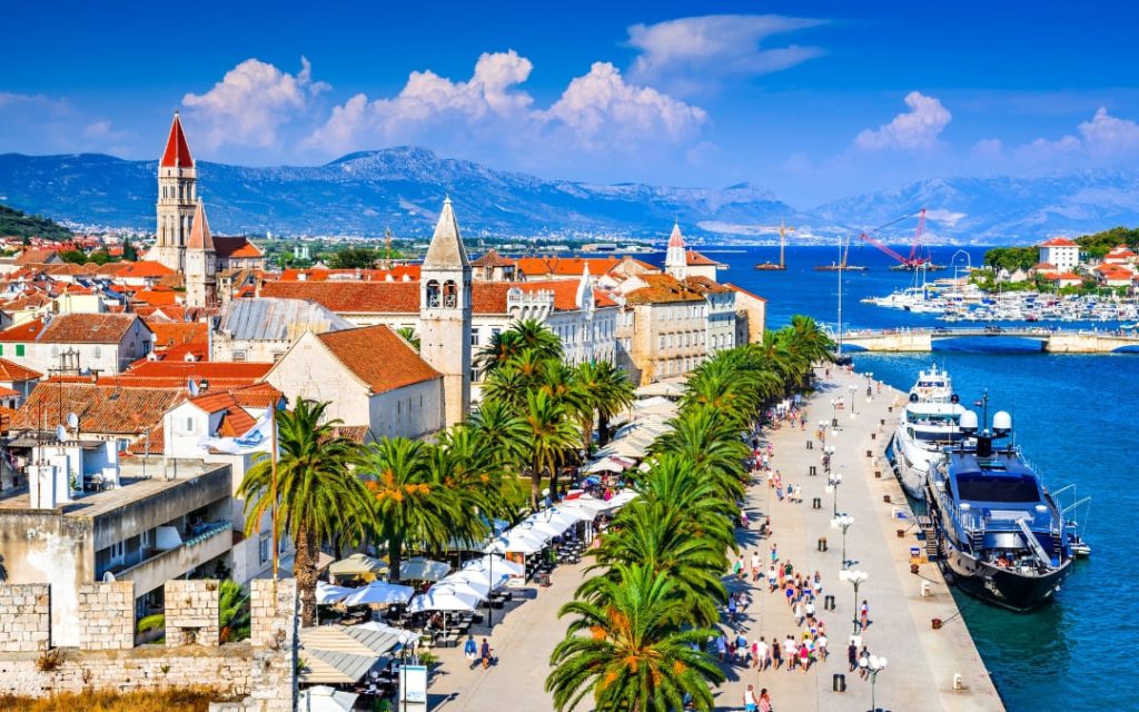 Panorama starego miasta Trogir z palmową promenadą, portem jachtowym i widokiem na Adriatyk
