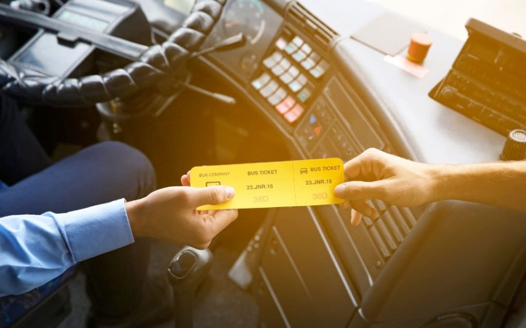 Pasażer odbierający bilet autobusowy od kierowcy wewnątrz autobusu komunikacji miejskiej 
