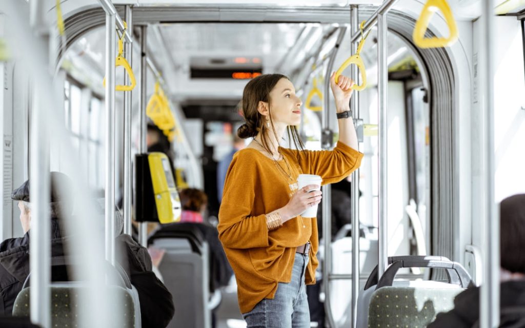 Pasażerka trzymająca uchwyt w autobusie komunikacji miejskiej podczas podróży po mieście