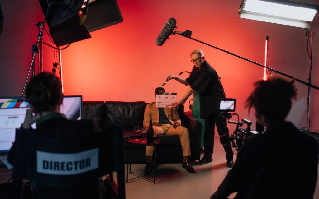Plan filmowy z ekipą produkcyjną, kamerą, mikrofonem i klapsem podczas nagrywania sceny

