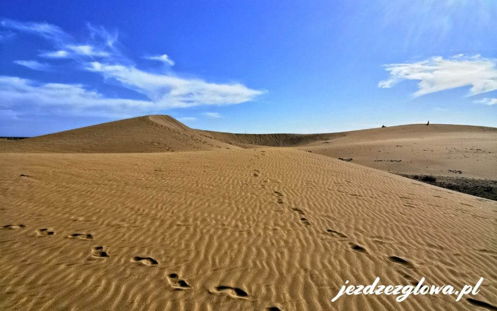Ślady na piasku i falujące wydmy Maspalomas w słoneczny dzień